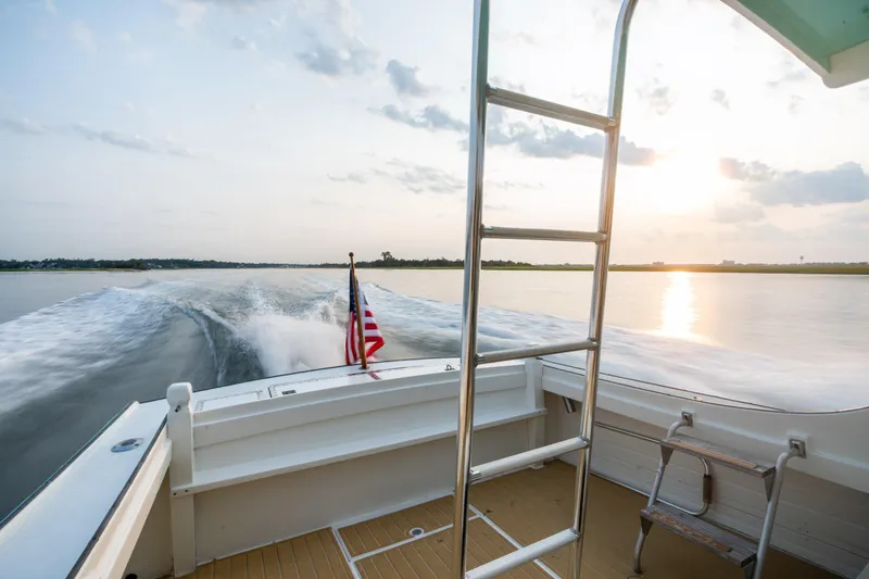 Slide: The Image of 1958 Albury Brothers boat cruising at sunset with American flag. - 48