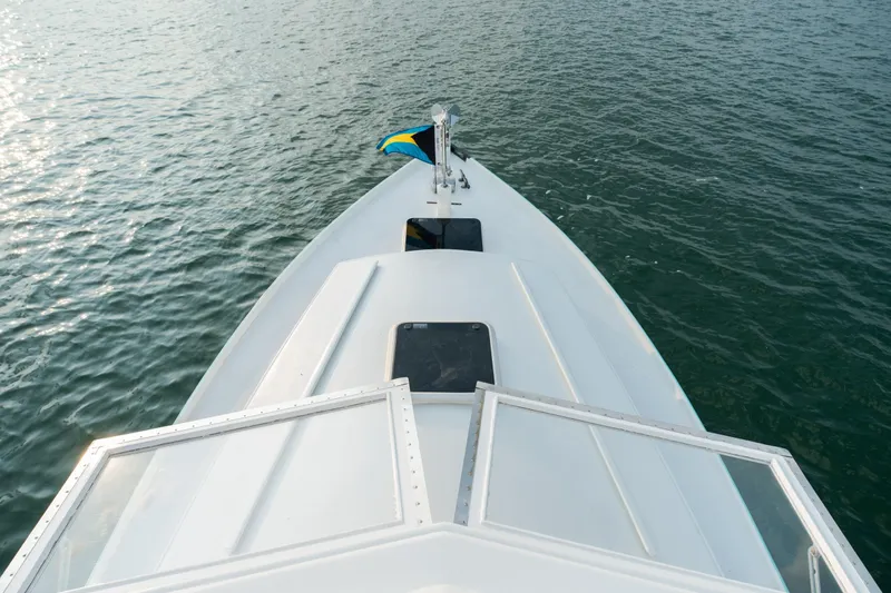 Slide: The Image of Bow view of a 1958 Albury Brothers boat with a flag, on calm water. - 87
