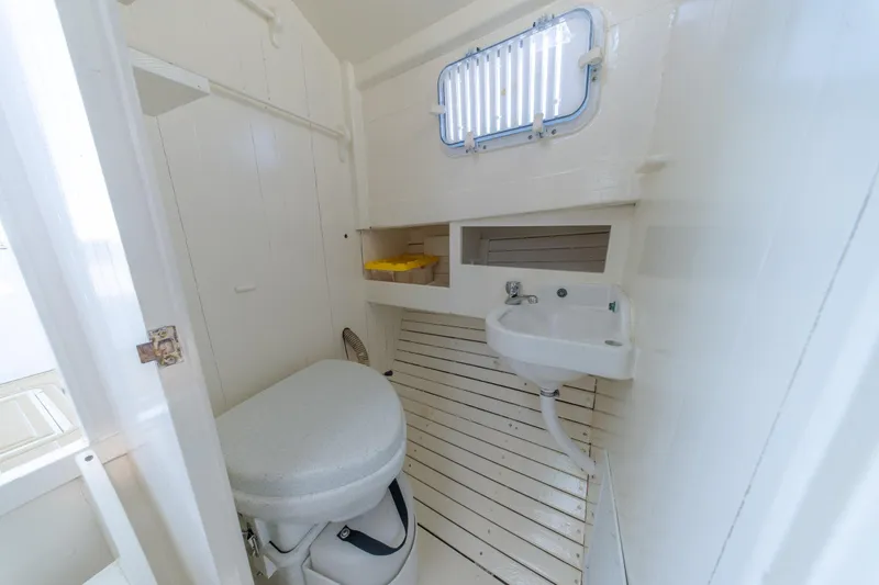 Slide: The Image of 1958 Albury Brothers boat bathroom with toilet, sink, and porthole window. - 81