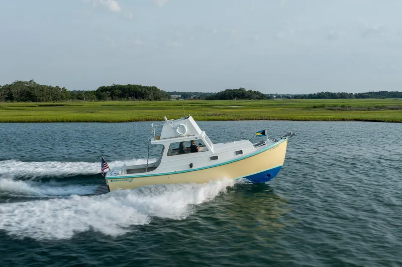 Slide: The Image of A 1958 Albury Brothers boat cruising on a scenic waterway with lush green surroundings. - 27