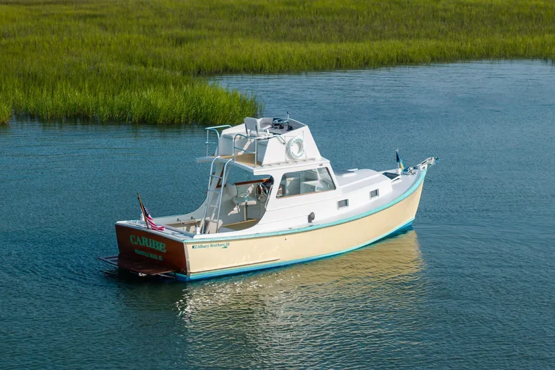 Slide: The Image of 1958 Albury Brothers boat on calm water near grassy shoreline. - 21