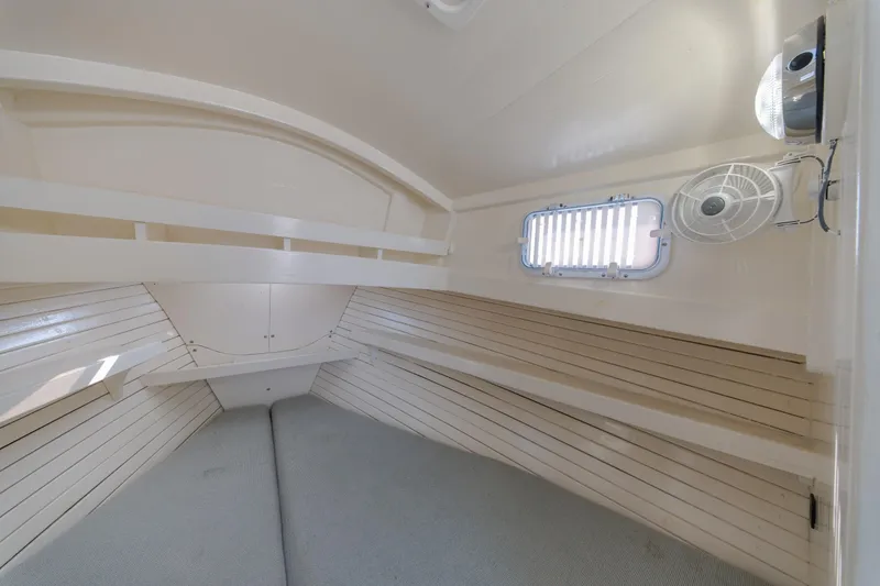 Slide: The Image of Interior cabin of a 1958 Albury Brothers boat, featuring wooden paneling and a small fan. - 77