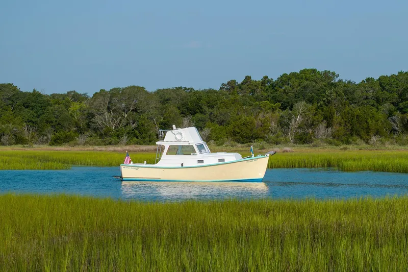 Slide: The Image of 1958 Albury Brothers boat on serene water, surrounded by lush greenery and clear blue sky. - 18