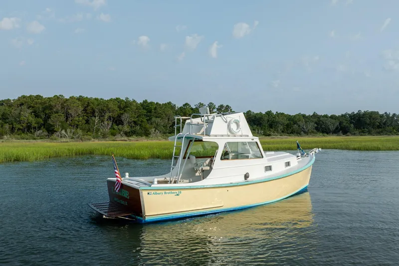 Slide: The Image of 1958 Albury Brothers boat on calm water, surrounded by lush greenery and clear skies. - 22