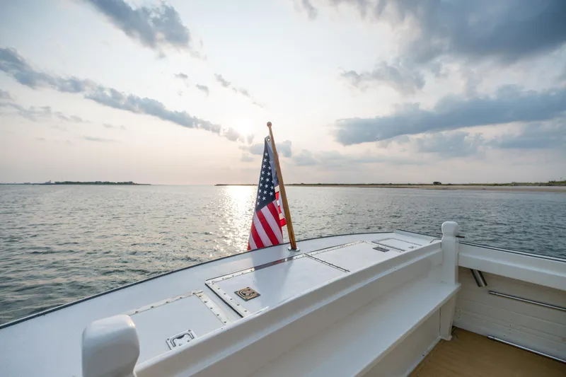 Slide: The Image of 1958 Albury Brothers boat with American flag on calm water at sunset. - 51