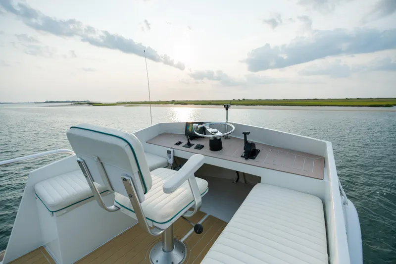 Slide: The Image of 1958 Albury Brothers boat helm with white seating, steering wheel, and serene water view. - 84