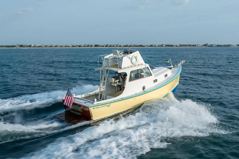 Slide: The Image of 1958 Albury Brothers boat cruising on open water with coastal background. - 40