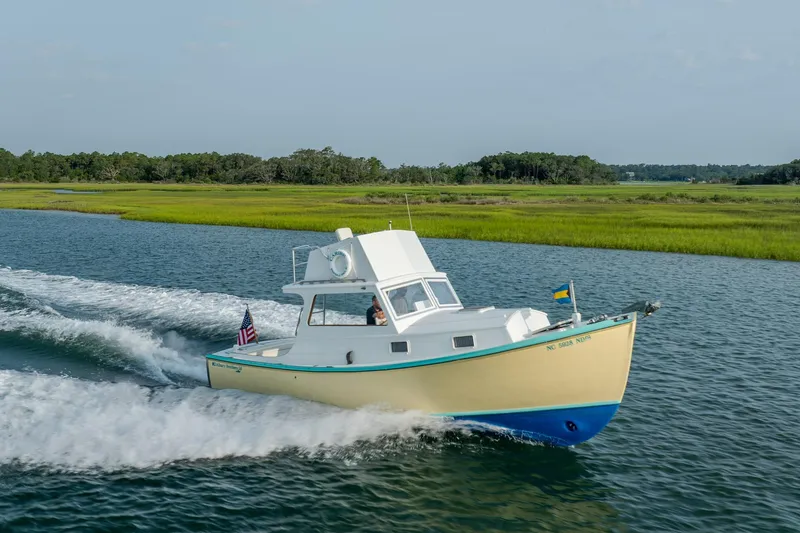 Slide: The Image of Vintage 1958 Albury Brothers boat cruising on a scenic waterway with lush greenery. - 29