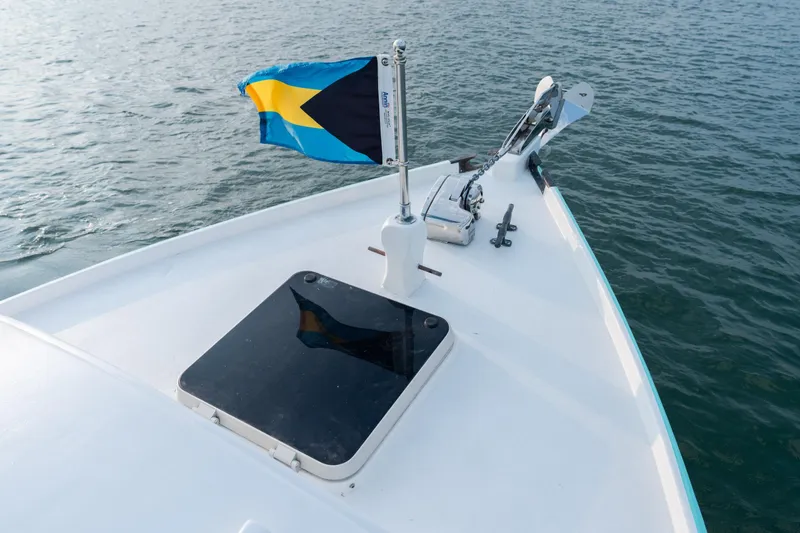 Slide: The Image of Bow of a 1958 Albury Brothers boat with a Bahamian flag on calm water. - 93