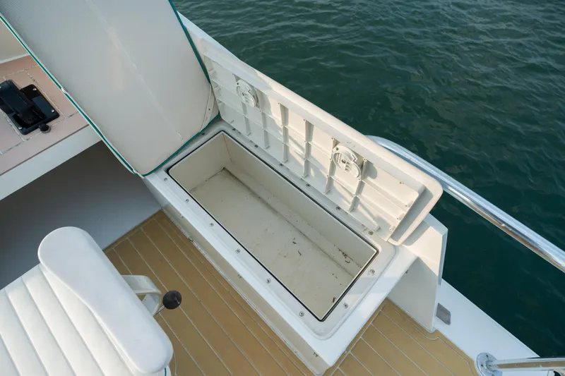 Slide: The Image of 1958 Albury Brothers boat with open storage compartment, white seating, and wooden deck by the water. - 91
