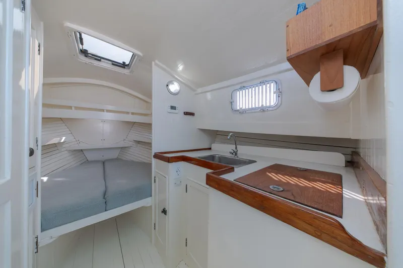 Slide: The Image of Interior of a 1958 Albury Brothers boat featuring a cozy cabin with bed and kitchenette. - 74