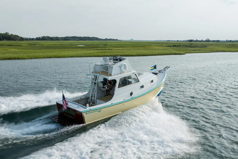 Slide: The Image of 1958 Albury Brothers boat cruising on a scenic waterway with lush green surroundings. - 26