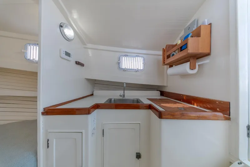 Slide: The Image of 1958 Albury Brothers boat interior with compact kitchen, wooden accents, and storage shelves. - 78
