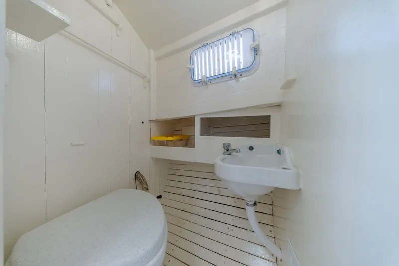 Slide: The Image of 1958 Albury Brothers boat interior with sink, toilet, and porthole window. - 80