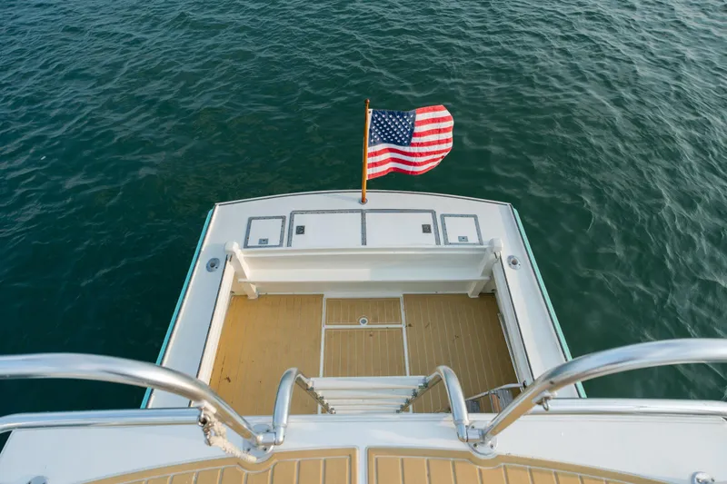 Slide: The Image of 1958 Albury Brothers boat stern with American flag, overlooking calm water. - 89