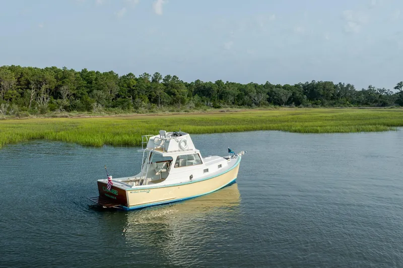 Slide: The Image of Vintage 1958 Albury Brothers boat on serene water with lush green shoreline. - 19