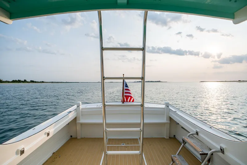 Slide: The Image of 1958 Albury Brothers boat deck with ladder, American flag, and serene ocean view at sunset. - 49