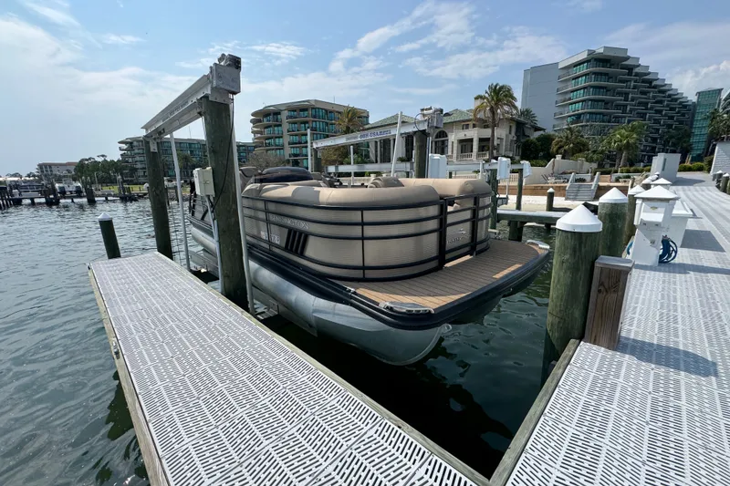 Slide: The Image of 2022 Bennington 23 LXFB pontoon boat docked at a marina with modern buildings. - 2