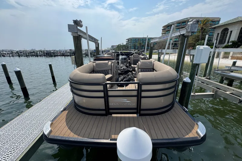 Slide: The Image of 2022 Bennington 23 LXFB pontoon boat docked at a marina with scenic waterfront views. - 5