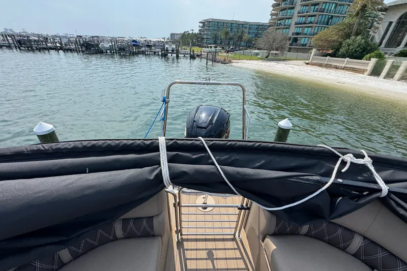 Slide: The Image of 2022 Bennington 23 LXFB boat docked by a waterfront with modern buildings. - 23