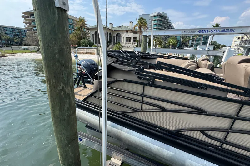 Slide: The Image of 2022 Bennington 23 LXFB pontoon boat docked near waterfront buildings. - 11