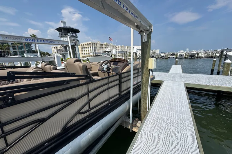 Slide: The Image of 2022 Bennington 23 LXFB pontoon boat docked at a marina under a clear blue sky. - 10