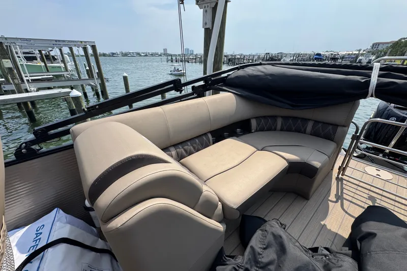 Slide: The Image of 2022 Bennington 23 LXFB boat interior with beige seating, docked by the water. - 21