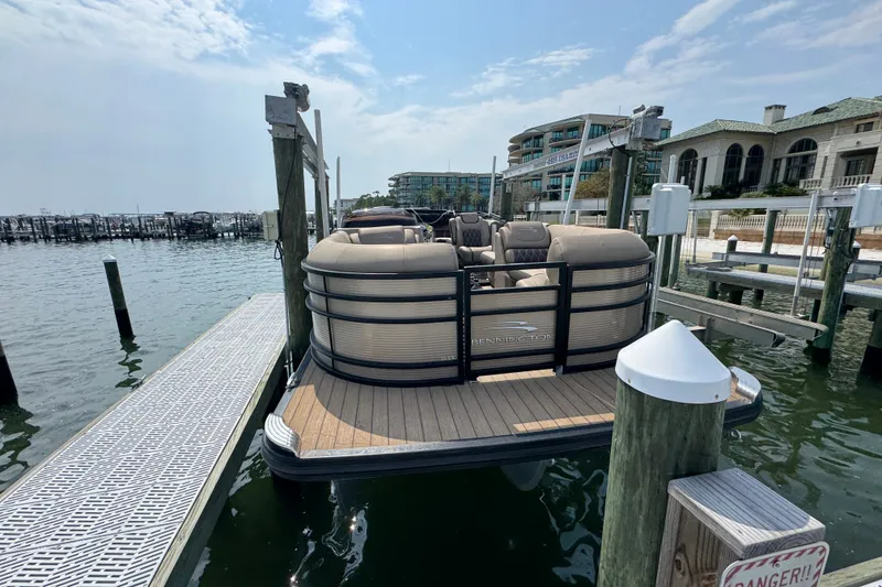 Slide: The Image of 2022 Bennington 23 LXFB pontoon boat docked at a marina under a partly cloudy sky. - 4
