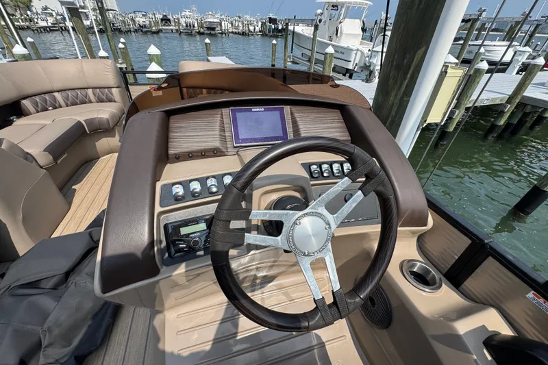 Slide: The Image of 2022 Bennington 23 LXFB boat dashboard with steering wheel and control panel at marina. - 16