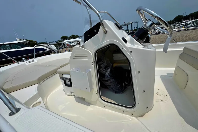 Slide: The Image of 2027 Boston Whaler 170 Montauk boat interior with open storage compartment and steering wheel. - 14