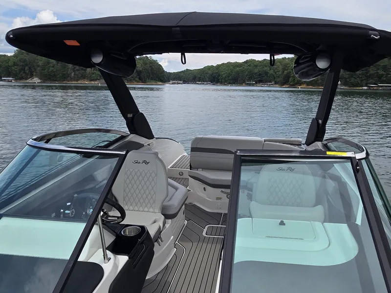 Slide: The Image of The image shows the cockpit of a 2025 Sea Ray SLX 260 Surf boat on a calm lake. - 26