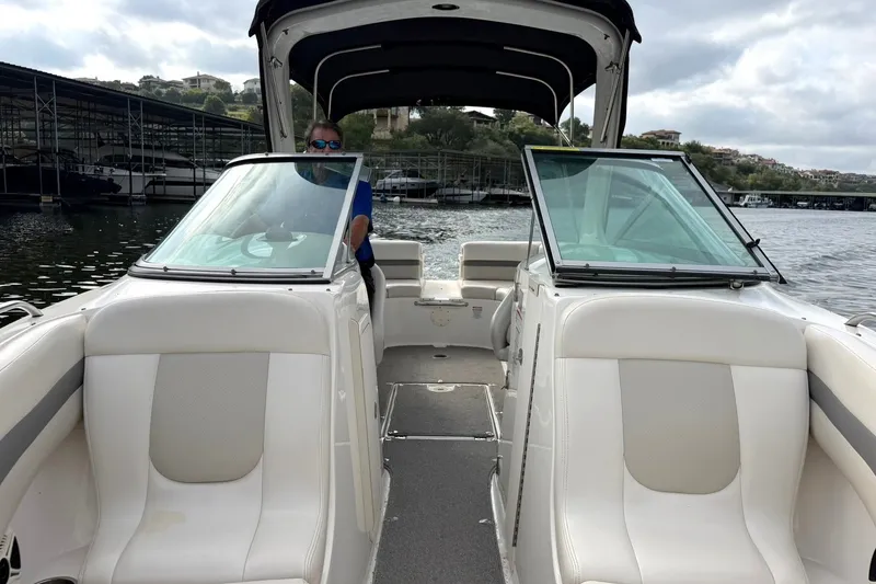 Slide: The Image of 2008 Chaparral 256 SSi boat interior with seating and windshield on a cloudy day. - 48
