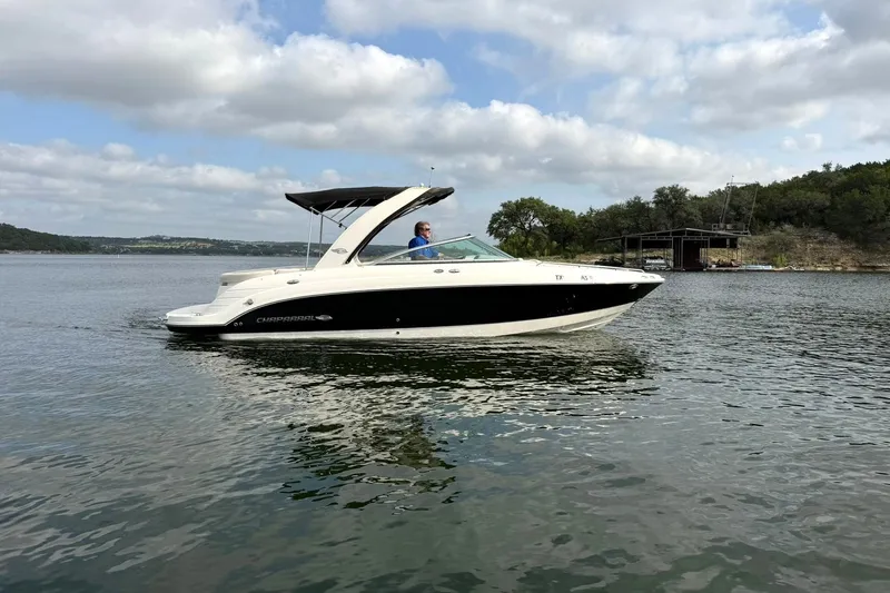 Slide: The Image of 2008 Chaparral 256 SSi boat cruising on a calm lake under a partly cloudy sky. - 16