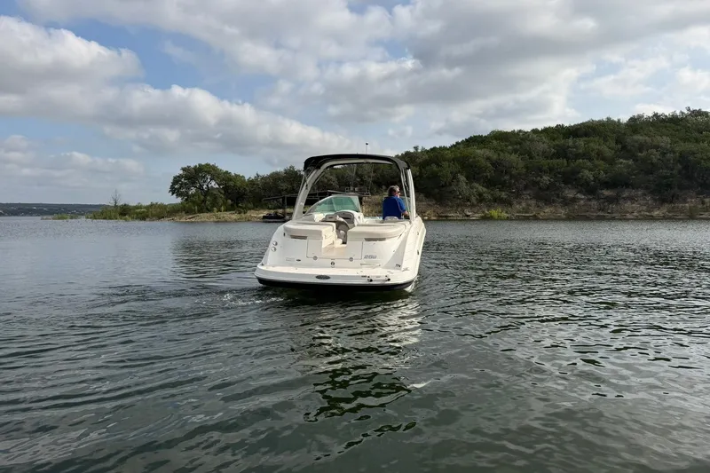Slide: The Image of 2008 Chaparral 256 SSi boat cruising on a serene lake with lush green shoreline. - 22