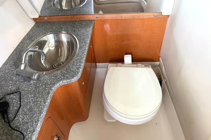 Slide: The Image of 2008 Chaparral 256 SSi boat bathroom with sink and toilet, featuring wood accents. - 39