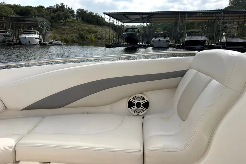 Slide: The Image of 2008 Chaparral 256 SSi boat interior with white seating and speaker, docked near marina. - 44
