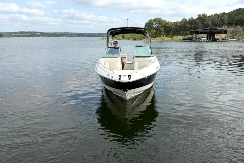 Slide: The Image of 2008 Chaparral 256 SSi boat cruising on a serene lake under a cloudy sky. - 15