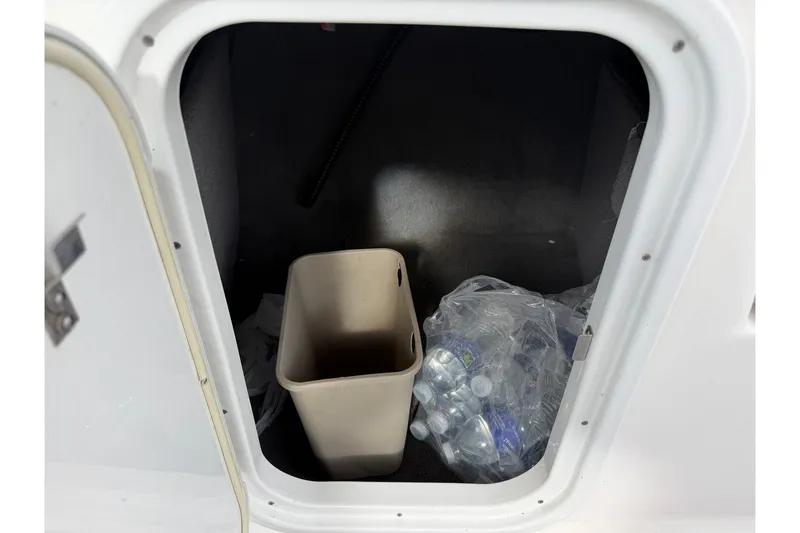 Slide: The Image of Storage compartment in a 2008 Chaparral 256 SSi boat with trash bin and water bottles. - 61