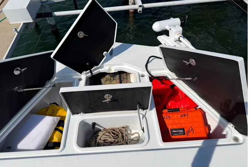Slide: The Image of Open storage compartments on a 2024 Costa Custom Boats 264HC, featuring safety gear and equipment. - 20
