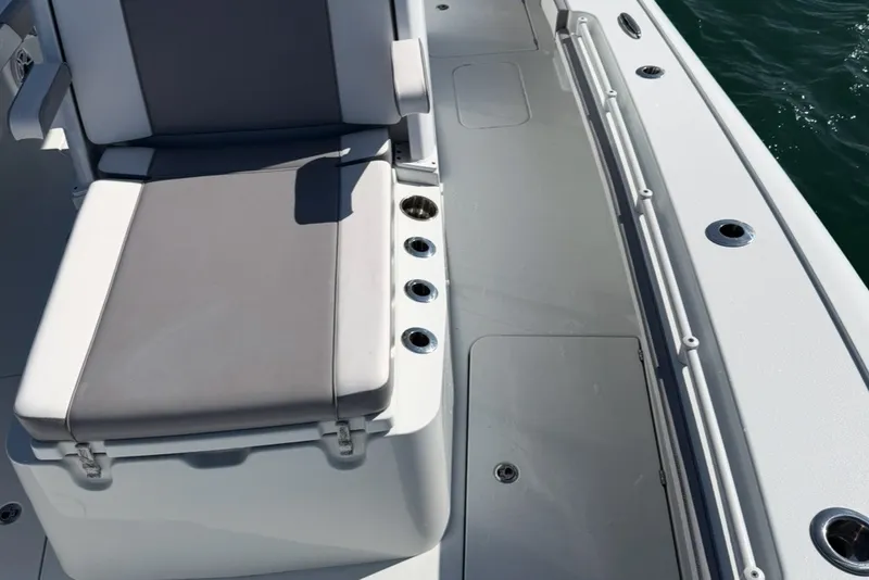 Slide: The Image of 2024 Costa Custom Boats 264HC deck with seating and cup holders, on calm water. - 16