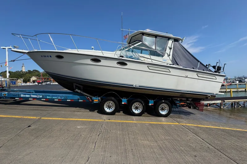 Slide: The Image of 1986 Tiara Yachts 3100 Open on trailer at marina, clear sky background. - 16