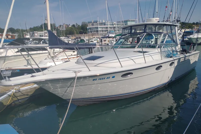 The Image of 1986 Tiara Yachts 3100 Open docked in a marina, surrounded by other boats. - 0