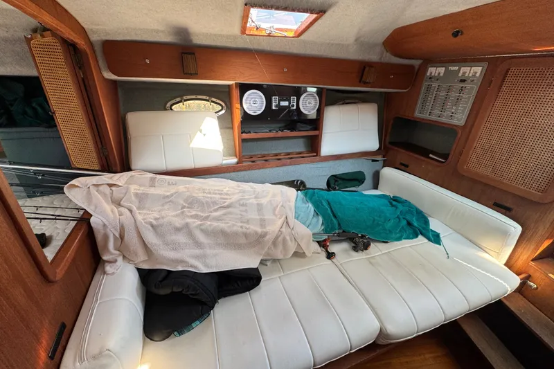Slide: The Image of Interior of a 1986 Tiara Yachts 3100 Open, featuring a cozy cabin with white seating. - 14