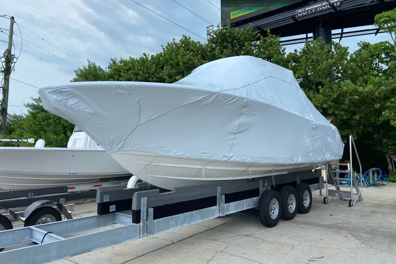 Slide: The Image of 2027 Sportsman Heritage 261 Center Console boat covered on a trailer, parked outdoors. - 1