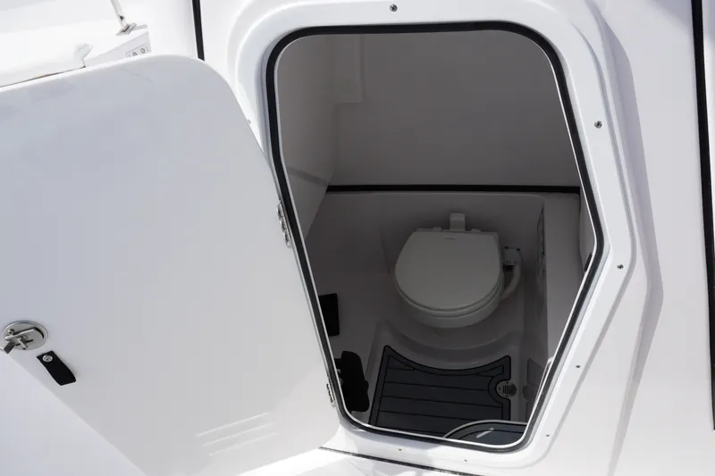 Slide: The Image of 2027 Sportsman Heritage 261 Center Console boat interior with open door revealing toilet. - 27