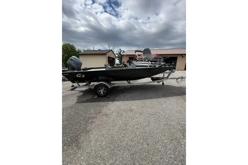 Slide: The Image of 2020 G3 Sportsman 1710 boat on trailer, parked outdoors under cloudy sky. - 12