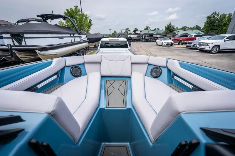Slide: The Image of 2026 ATX Surf Boats 22 Type-S interior with blue and white seating, parked in a marina. - 19