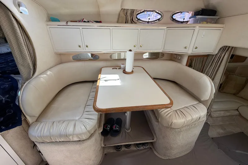 Slide: The Image of 1999 Sea Ray Sundancer 310 interior with cozy dining area and white leather seating. - 24