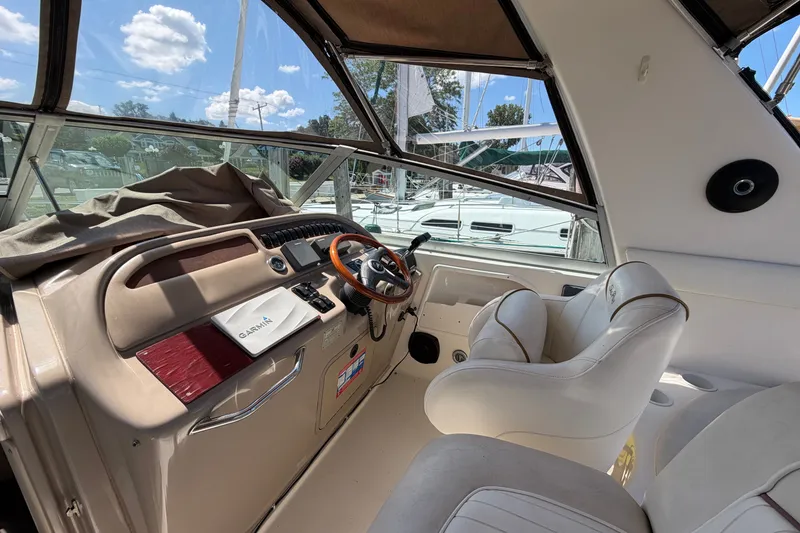 Slide: The Image of 1999 Sea Ray Sundancer 310 cockpit with steering wheel, Garmin device, and white seating. - 15