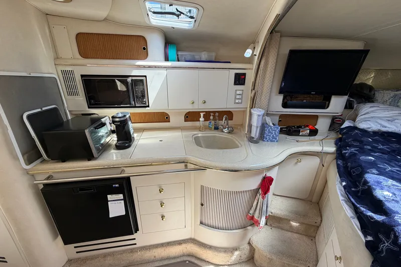 Slide: The Image of 1999 Sea Ray Sundancer 310 interior with kitchenette, microwave, and cozy sleeping area. - 26